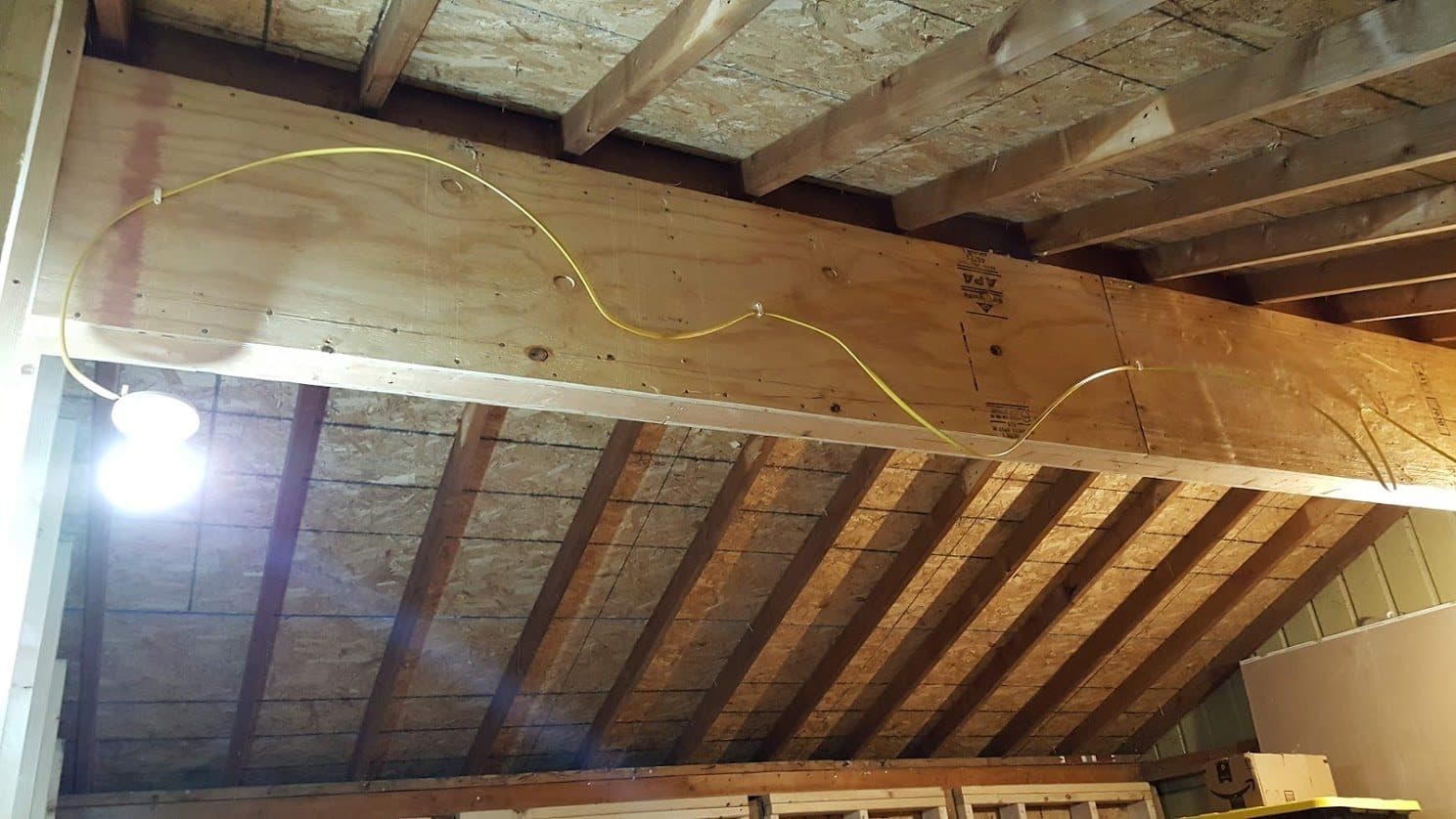 The box beam carrying the roof structure across an interior opening, with framing and decking above