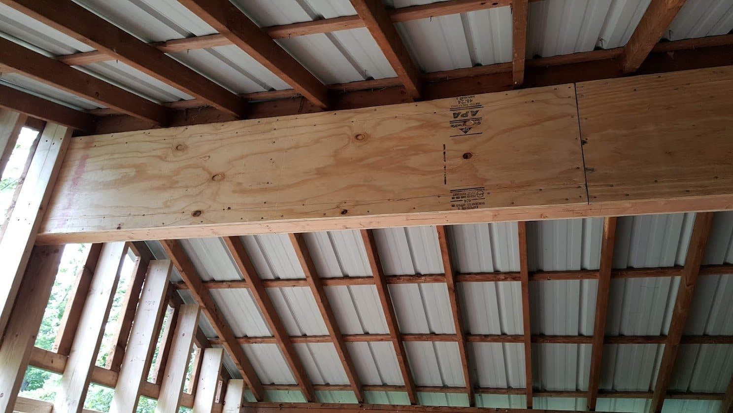 Underside of the APA-rated structural plywood box beam spanning beneath the metal roof framing