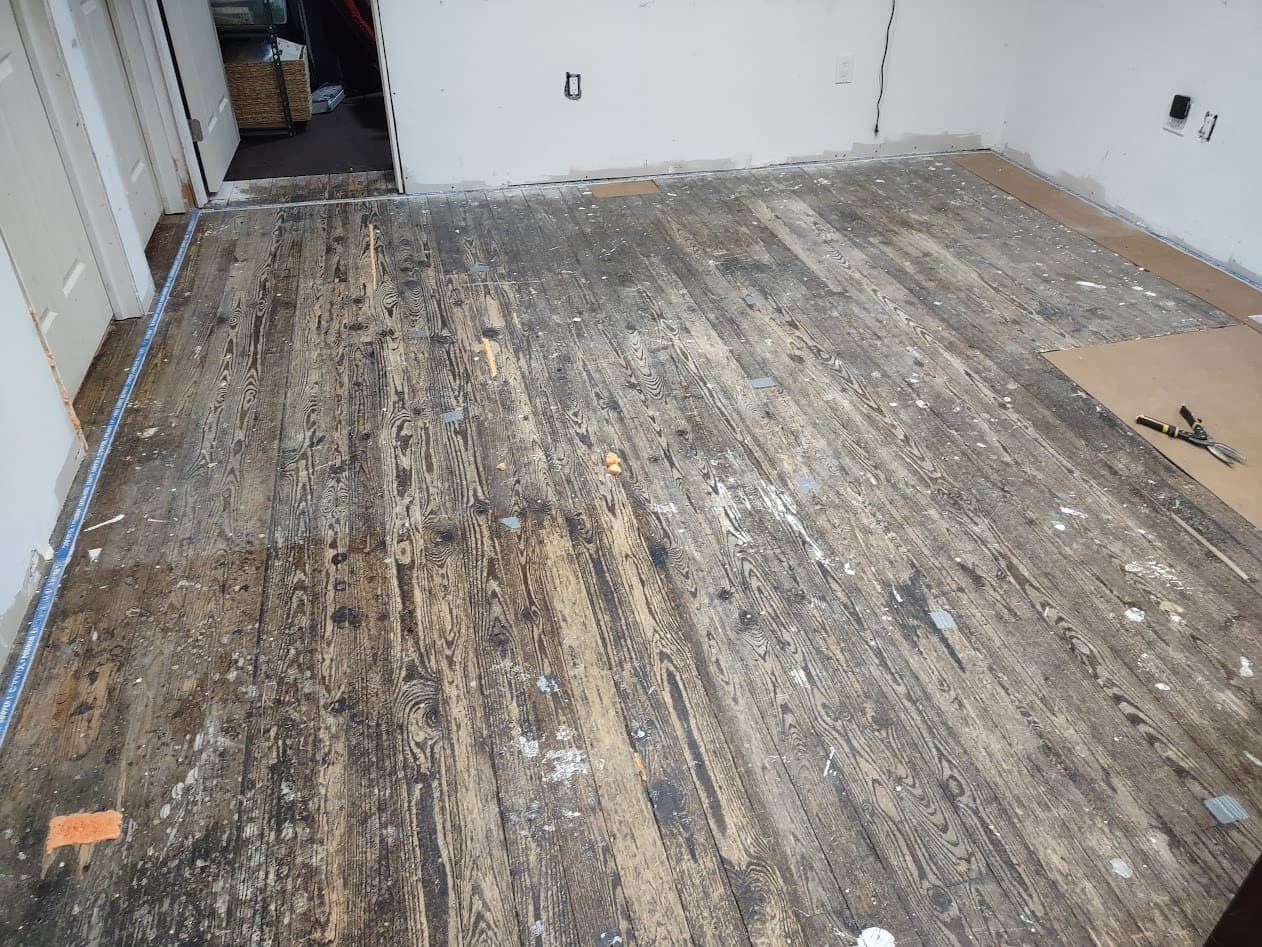 The room stripped down to its original wood plank subfloor before the new carpet went in