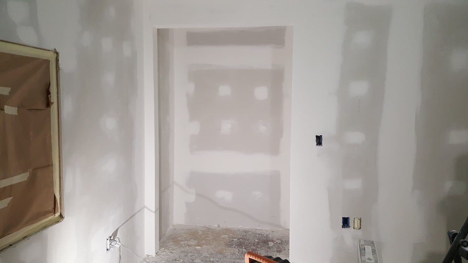 Room with taped and mudded drywall walls and a finished doorway opening, fastener dimples coated