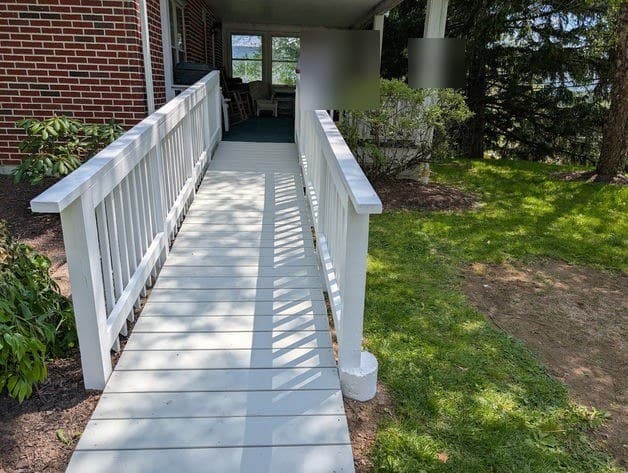 The painted white ramp in use, leading up to the covered porch