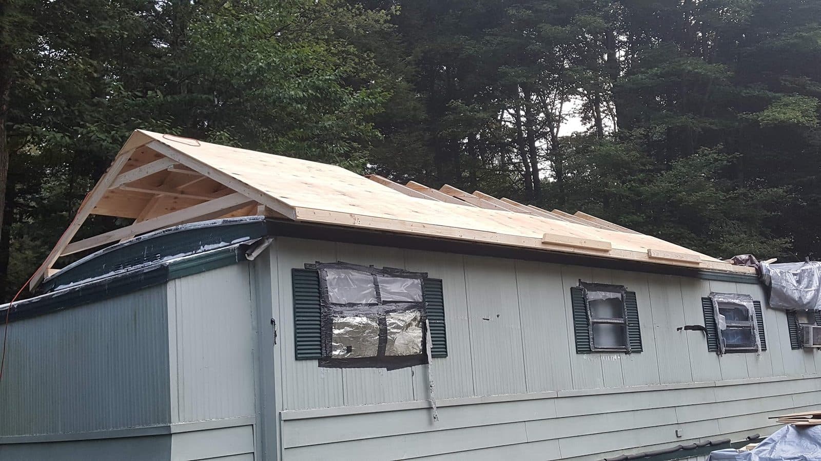 New gabled truss roof structure built over the mobile home with the deck sheathed
