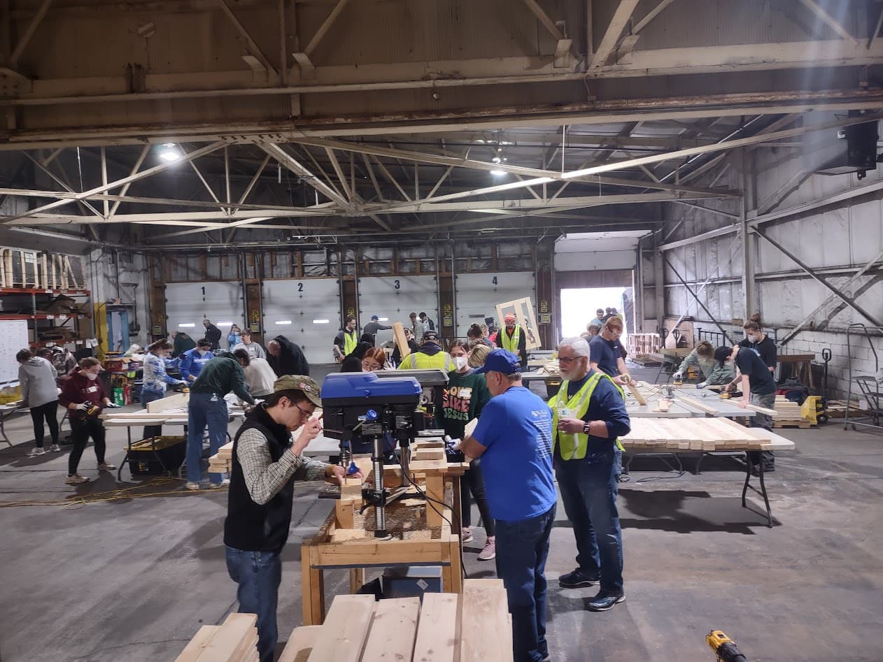 Volunteers drilling and assembling bed frames at the drill-press station