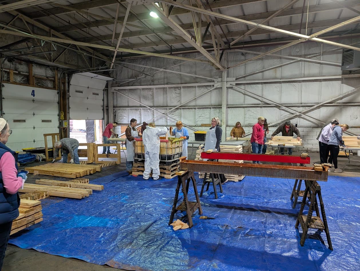 Volunteers staining and finishing bed rails on the tarp line